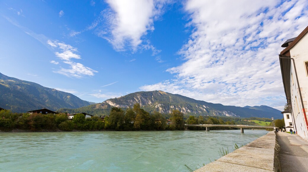 Waterfront view of Inn river along Inn promenade with mountain, blue sky in Rattenberg, Austria, Europe.