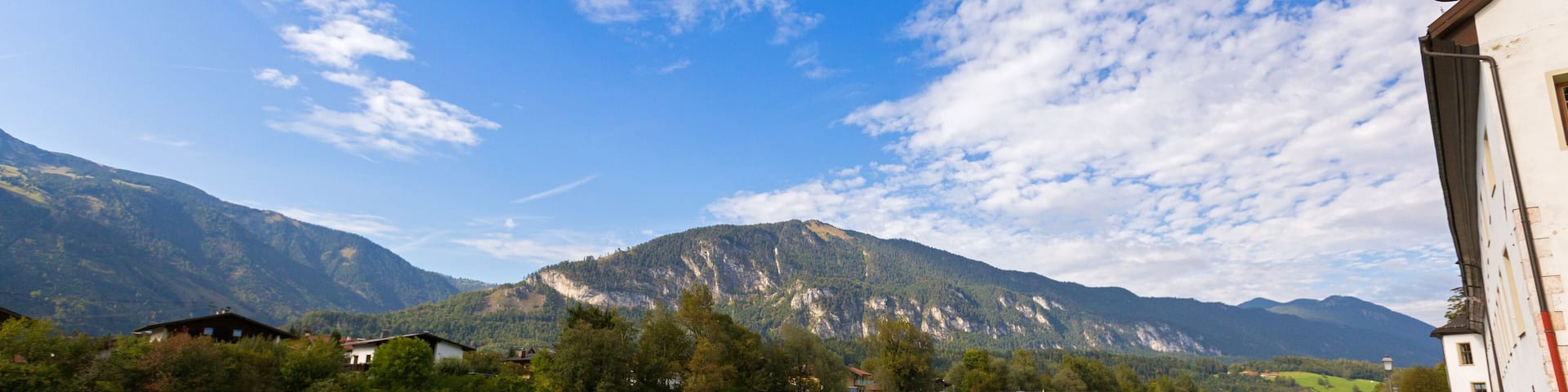 Waterfront view of Inn river along Inn promenade with mountain, blue sky in Rattenberg, Austria, Europe.