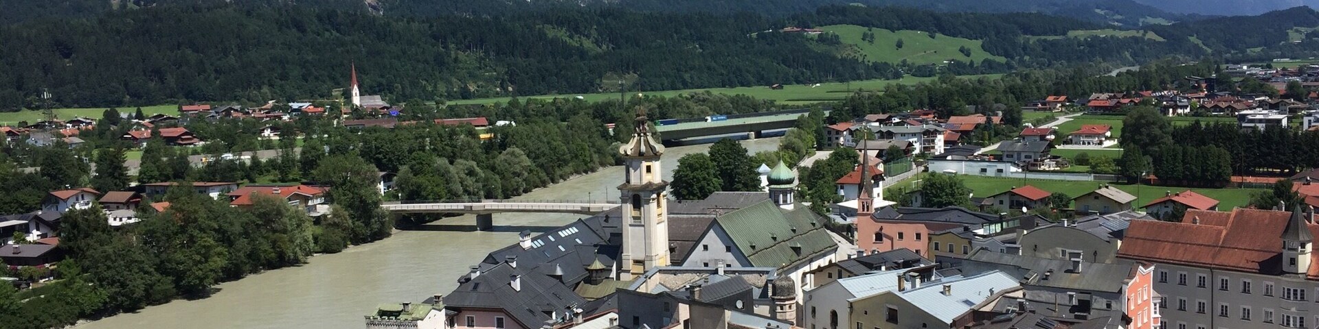 A town with a river, mountains, and a bridge.