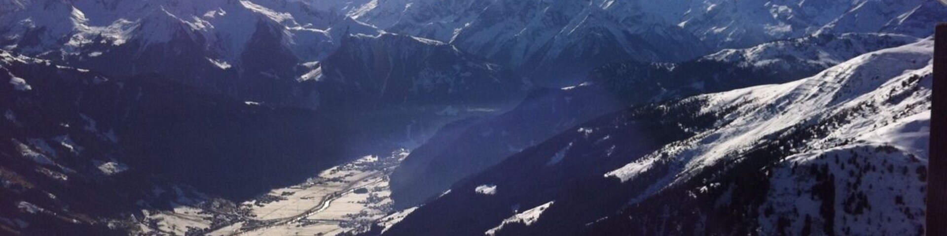 A snowy mountain landscape with a clear sky and a sun shining from the left.