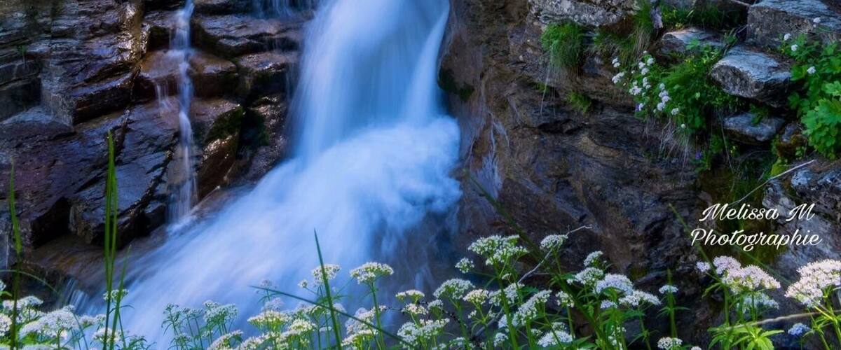 A waterfall cascading over rocky terrain surrounded by lush greenery.