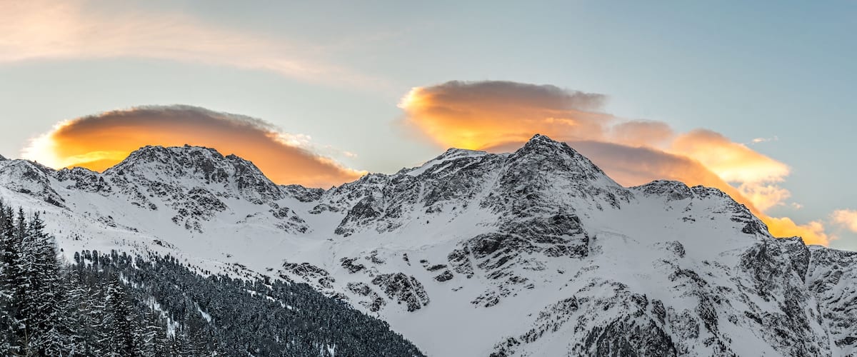 A snow-covered mountain range with a sunset.