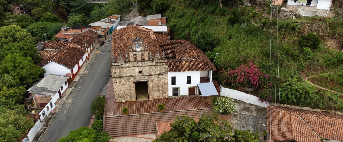 A historic town with terracotta-roofed buildings, a narrow street, and lush greenery.