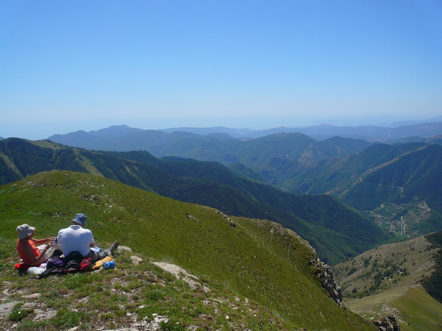 Un paysage montagneux avec des randonneurs sur une crête herbeuse.