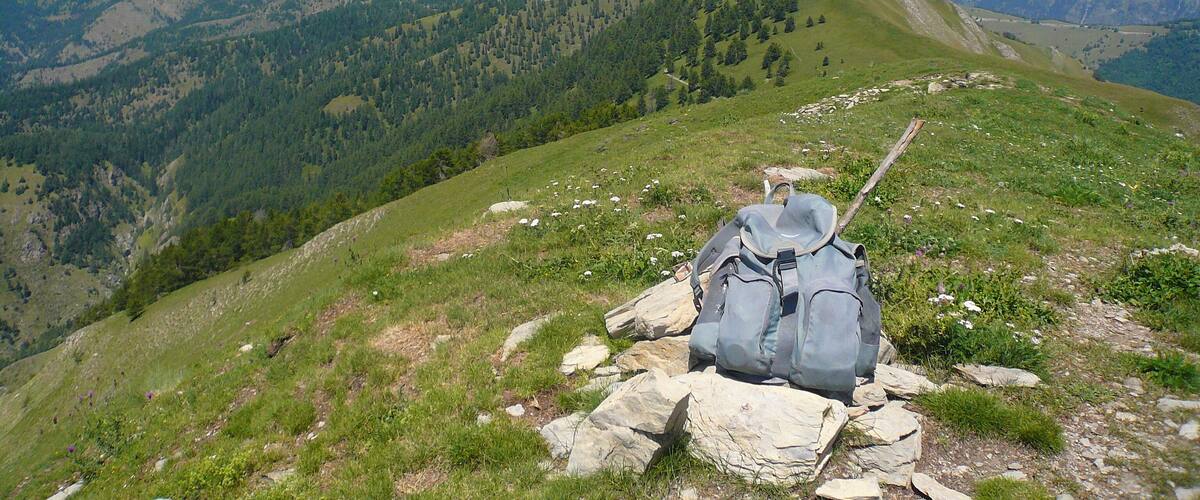 A backpack on a rocky path with a mountain range in the background.