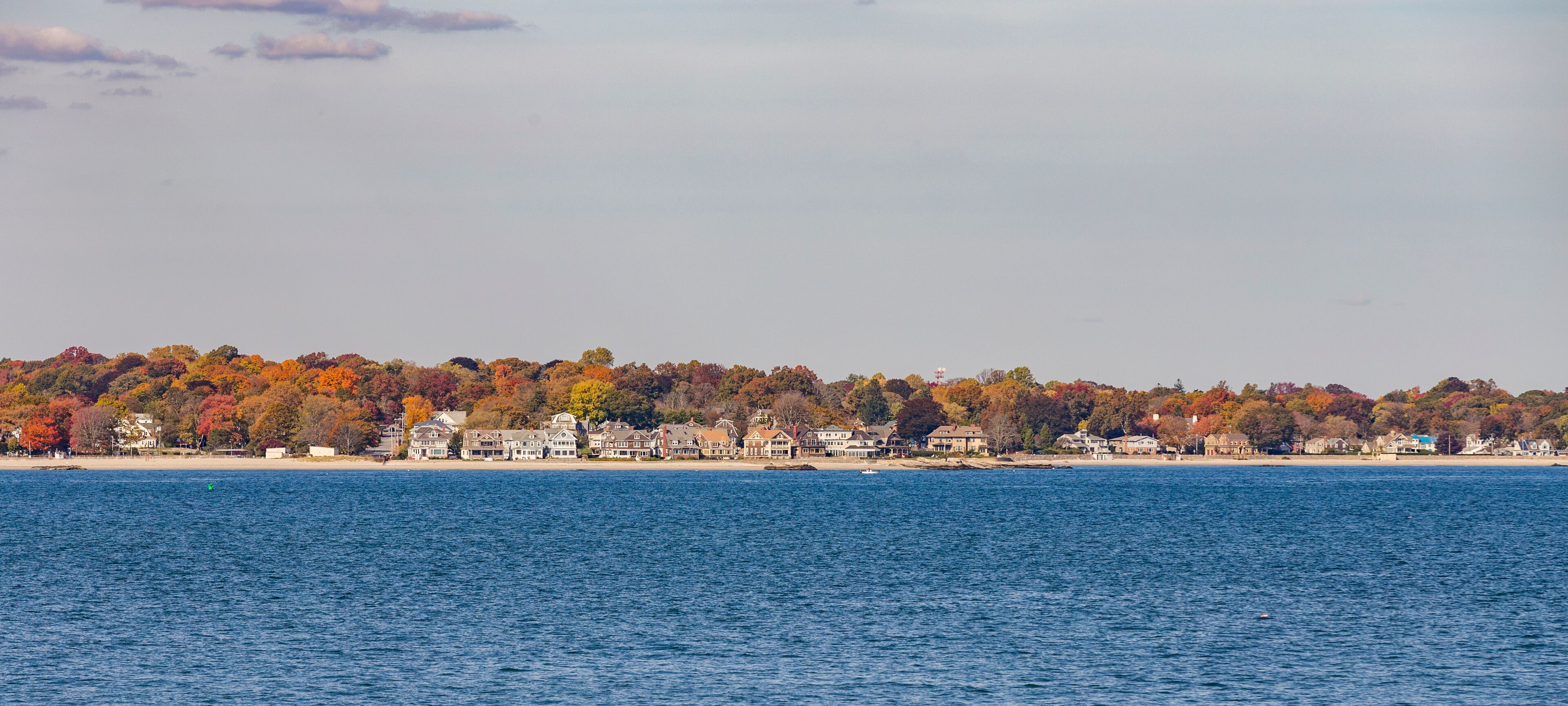 A coastal town with autumn-colored trees and houses along the shoreline.