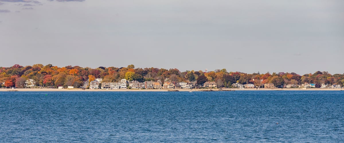 A coastal town with autumn-colored trees and houses along the shoreline.