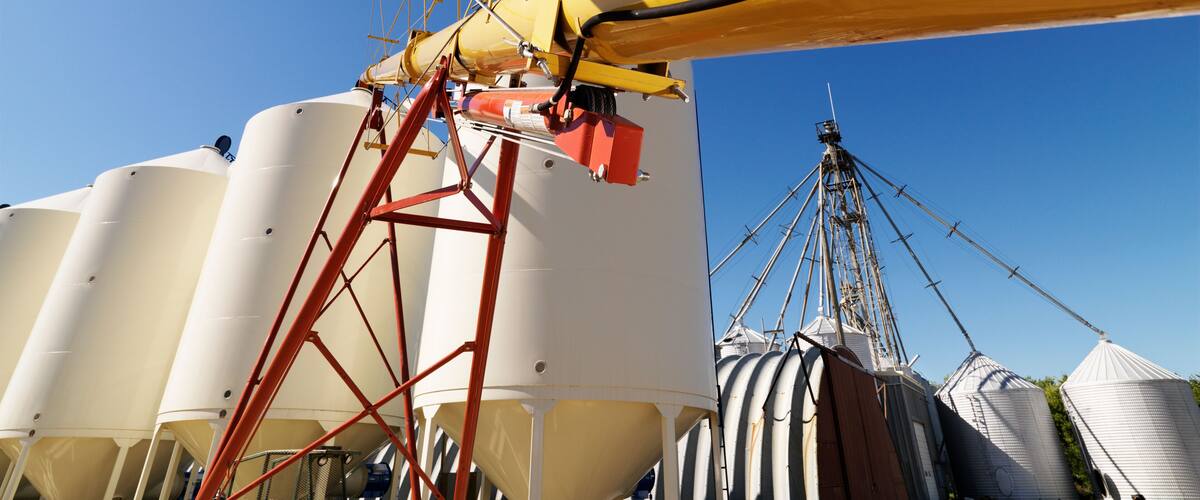 A grain elevator with large silos and a yellow crane.