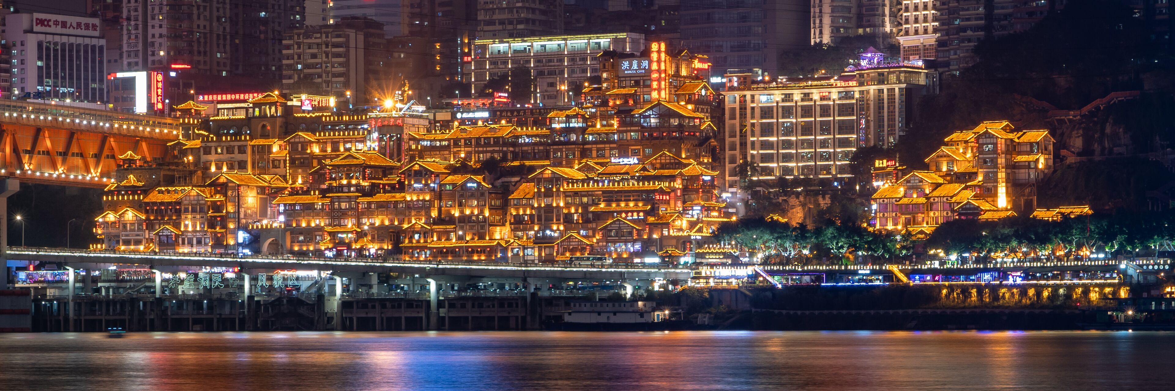Night neon ight pano view of historic traditional architecture in Hongya Dong cave by Jialing river in Chongqing, China