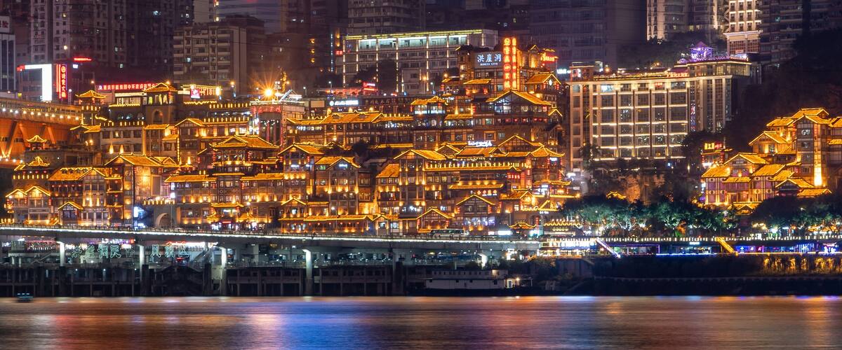 Night neon ight pano view of historic traditional architecture in Hongya Dong cave by Jialing river in Chongqing, China