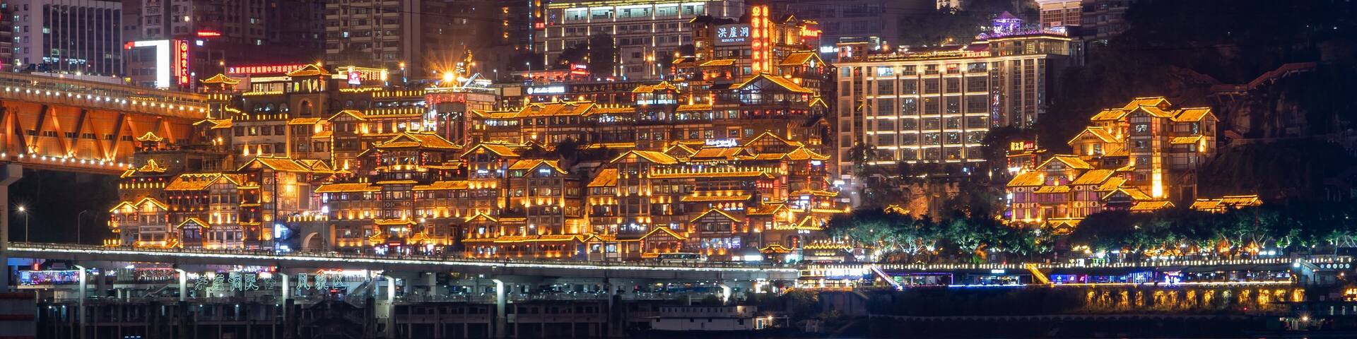 Night neon ight pano view of historic traditional architecture in Hongya Dong cave by Jialing river in Chongqing, China