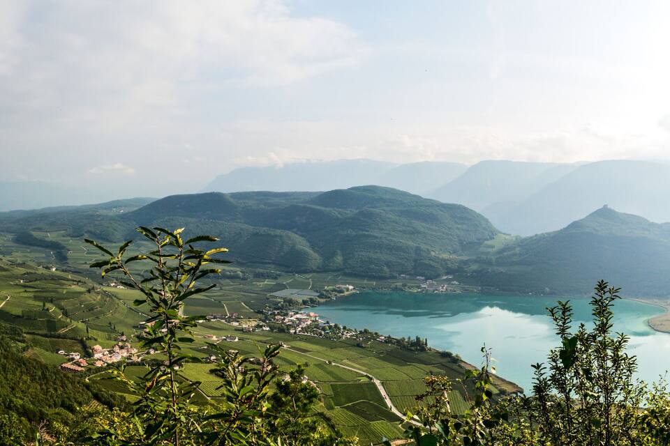 A mountainous landscape with terraced fields, a church, and a lake.