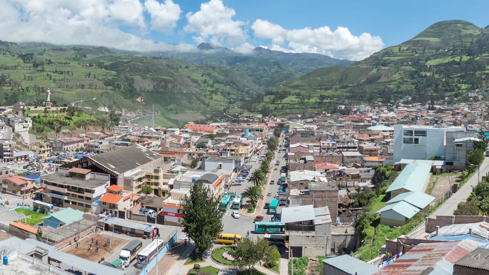 A town nestled in a valley with green hills in the background.