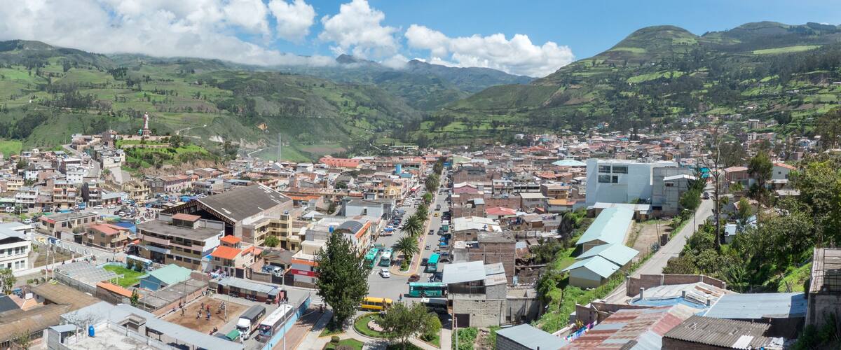 A town nestled in a valley with green hills in the background.