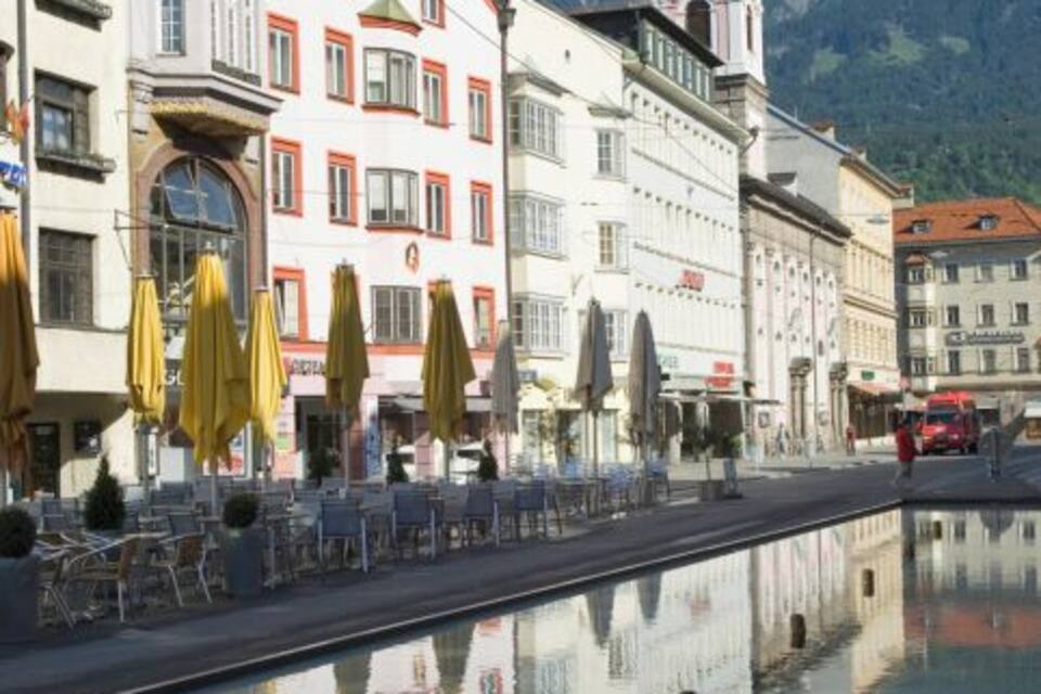 A canal reflecting buildings and mountains.