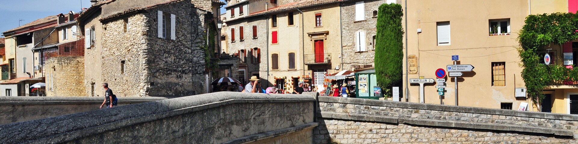 A stone bridge with arches, historic buildings, and a clear blue sky.