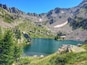 A mountain lake surrounded by rocky terrain and green vegetation.