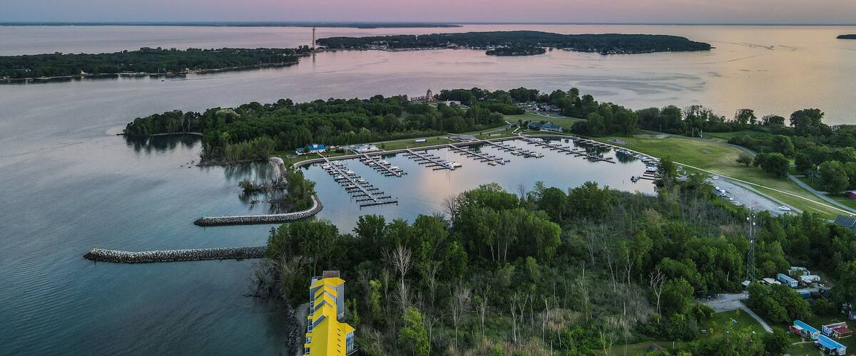 A marina with boats, a lighthouse, and a bridge in the background.