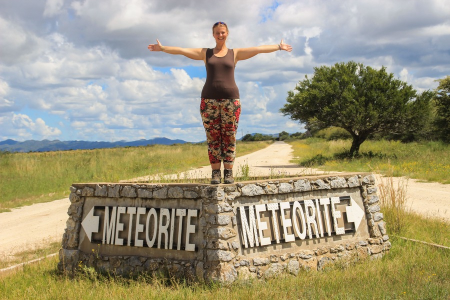 The largest meteorite in the world at Grootfontein, Namibia. White girl tourist stands on the sign