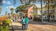 Une rue historique bordée de bâtiments aux couleurs vives, de palmiers et de piétons.