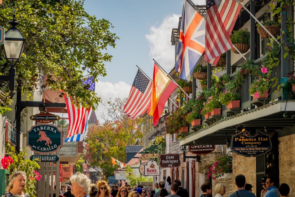 A bustling street with flags, shops, and pedestrians.