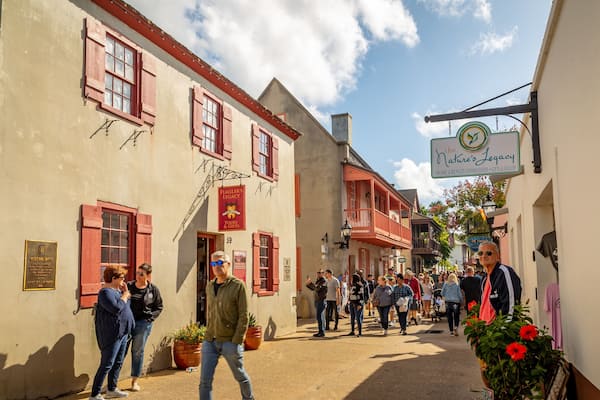 A bustling street with historic buildings, a sign for 'The Nature's Legacy' shop, and a plaque for 'Oliver's House'.