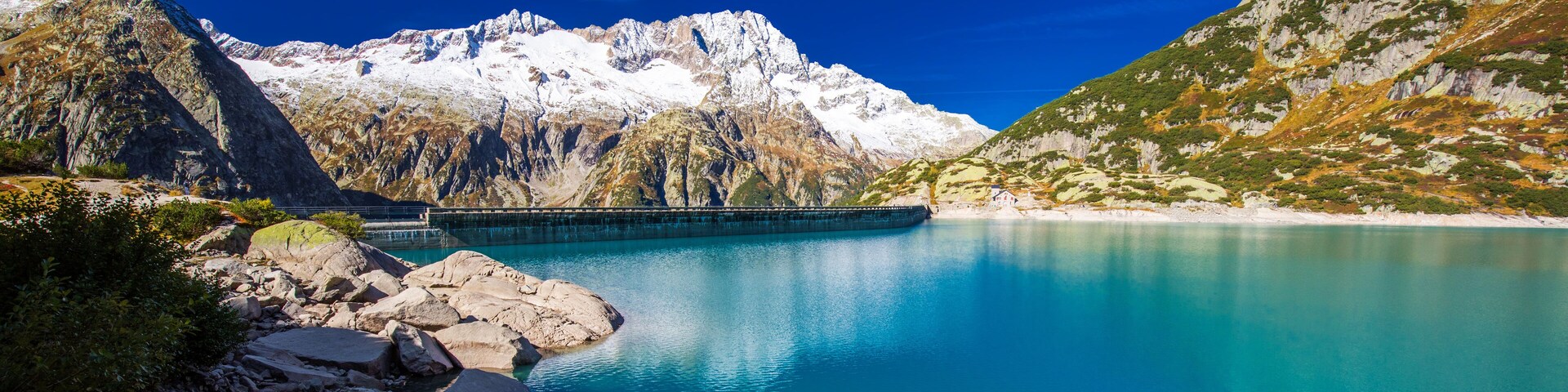 Un lago de montaña con una presa y costas rocosas.
