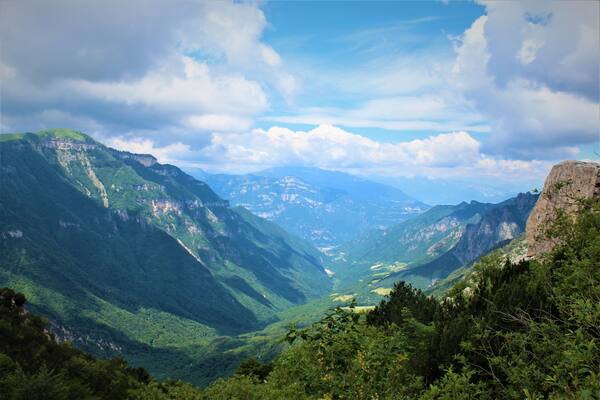 Paesaggio montuoso con valli verdeggianti e scogliere rocciose.