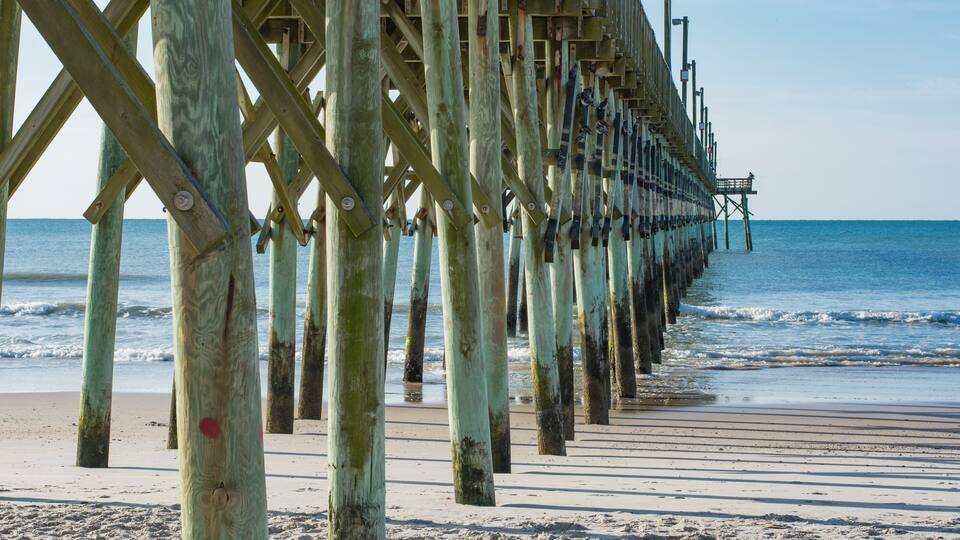 A wooden pier extending into the ocean with a clear sky above.