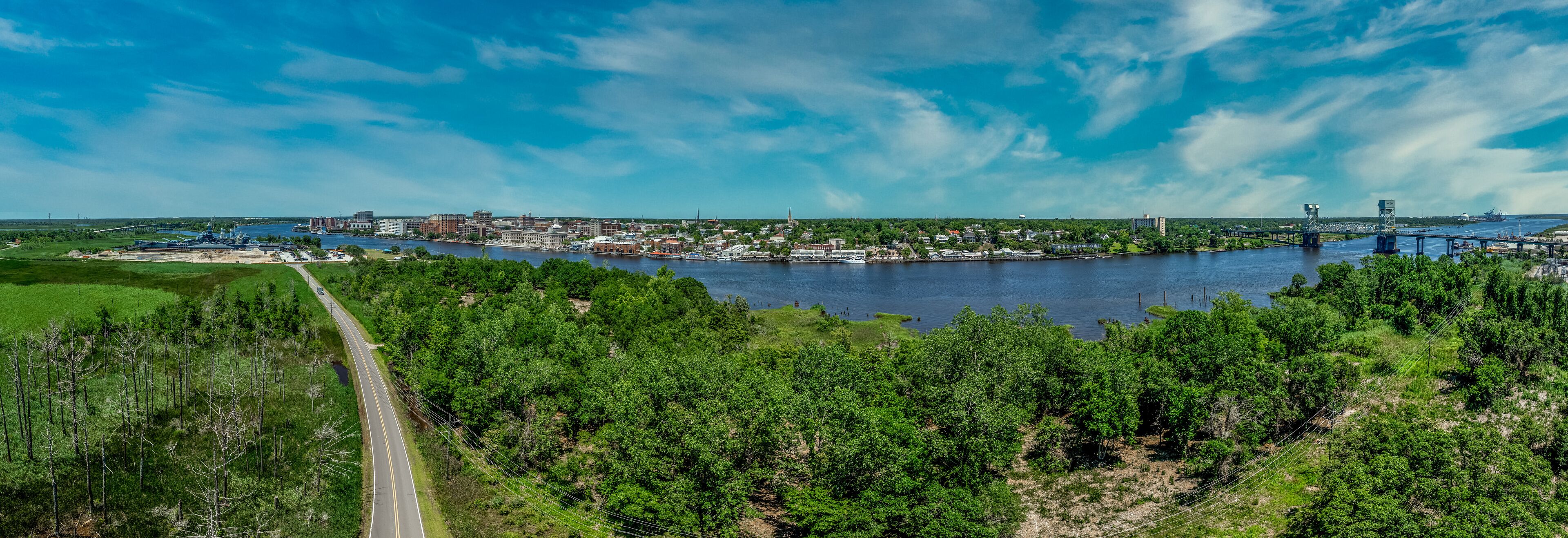 Aerial panorama view of Wilmington North Carolina historic district along the Cape Fear river, with the North Carolina battleship with cloudy sky
