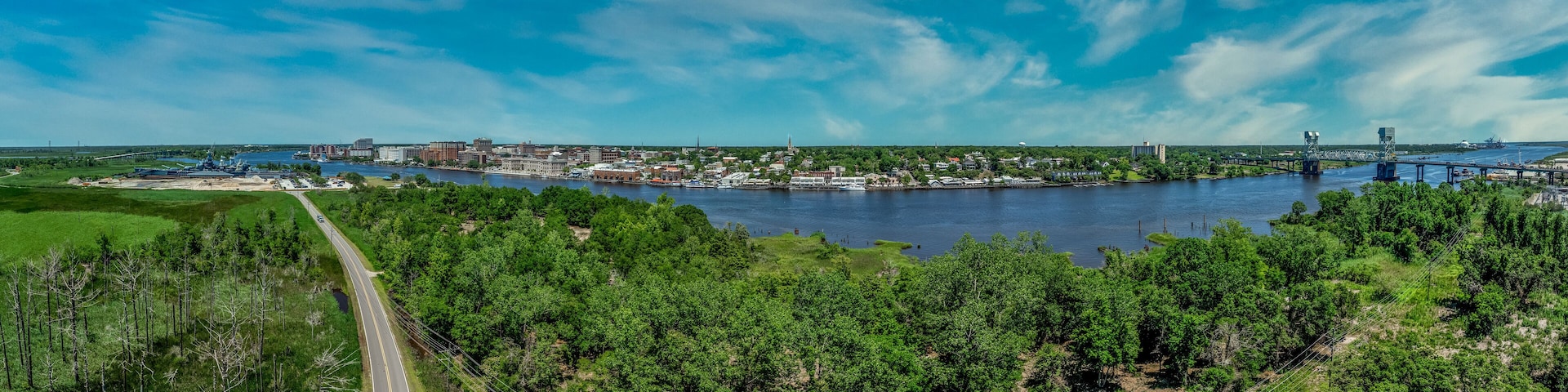 Aerial panorama view of Wilmington North Carolina historic district along the Cape Fear river, with the North Carolina battleship with cloudy sky
