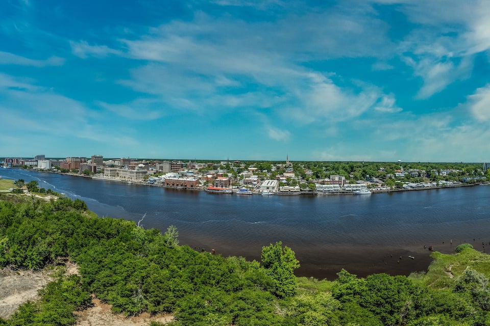 Um rio serpenteando por uma cidade com áreas industriais e espaços verdes.