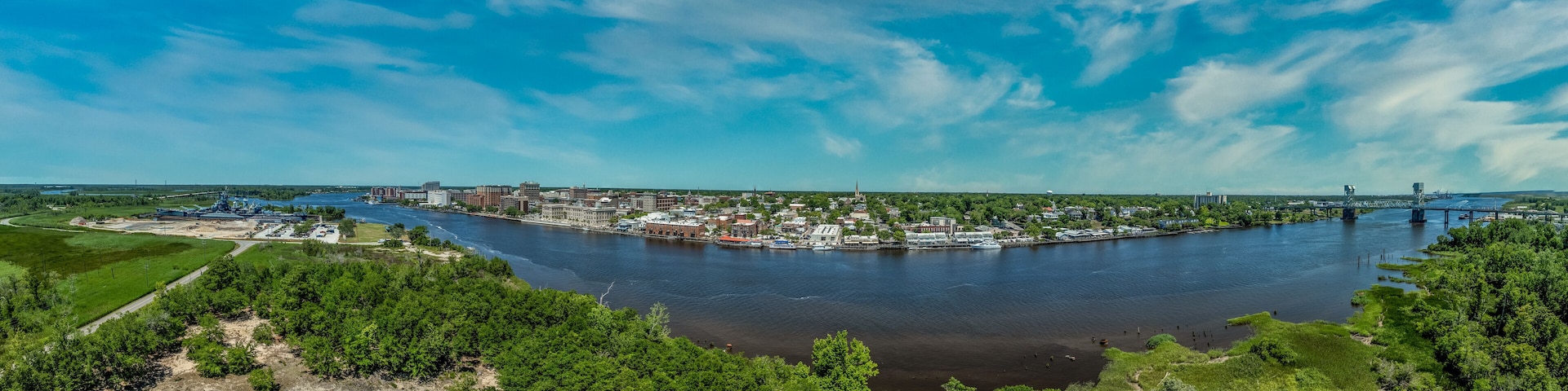 Aerial panorama view of Wilmington North Carolina historic district along the Cape Fear river, with the North Carolina battleship with cloudy sky
