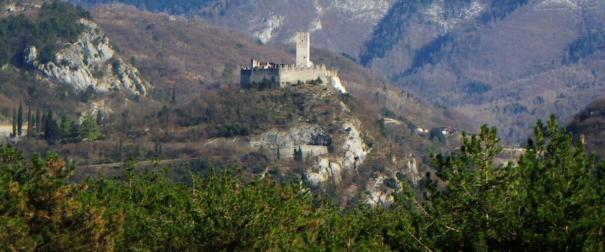 A castle on a hill with snow-capped mountains in the background.