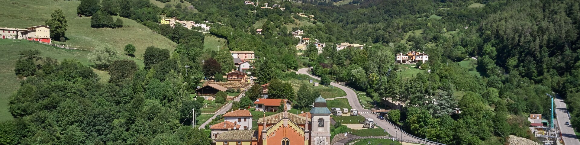 Un pueblo montañoso con una iglesia destacada, caminos serpenteantes y abundante vegetación.