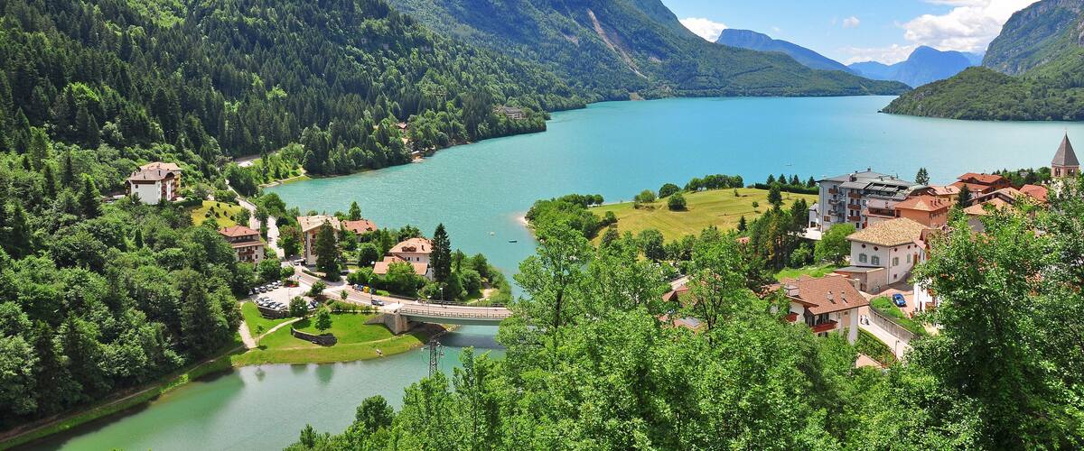 A mountainous landscape with a lake, a bridge, and buildings.