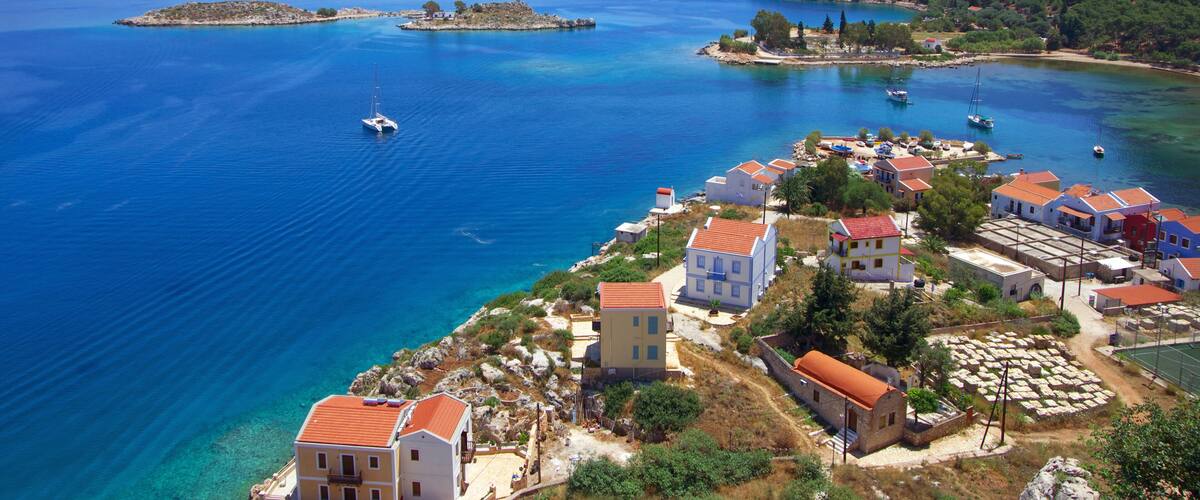 A coastal village with clear blue waters, small islands, and traditional buildings.