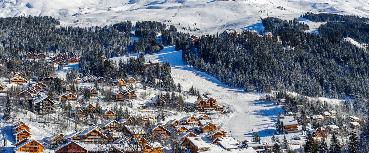 A snow-covered mountain with a ski resort and lodge buildings.