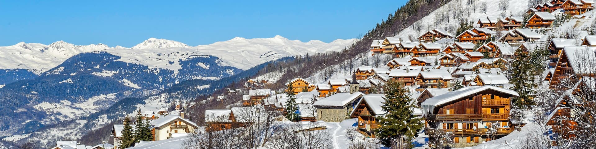 A snow-covered mountain village with wooden houses and a clear blue sky.