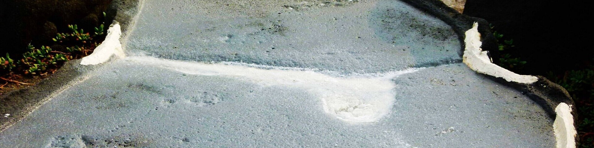 Una superficie de concreto con bordes irregulares y manchas de material blanco.