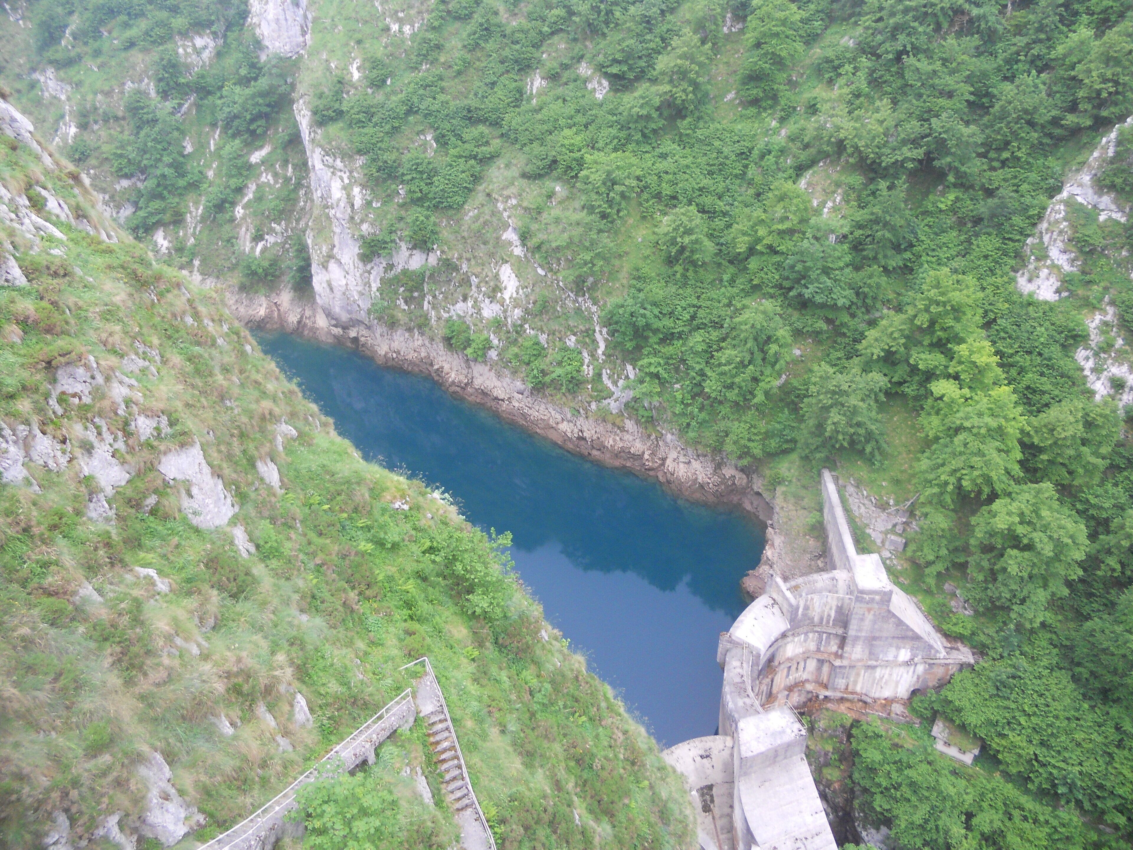 A deep blue lake surrounded by steep, rocky cliffs and lush greenery.