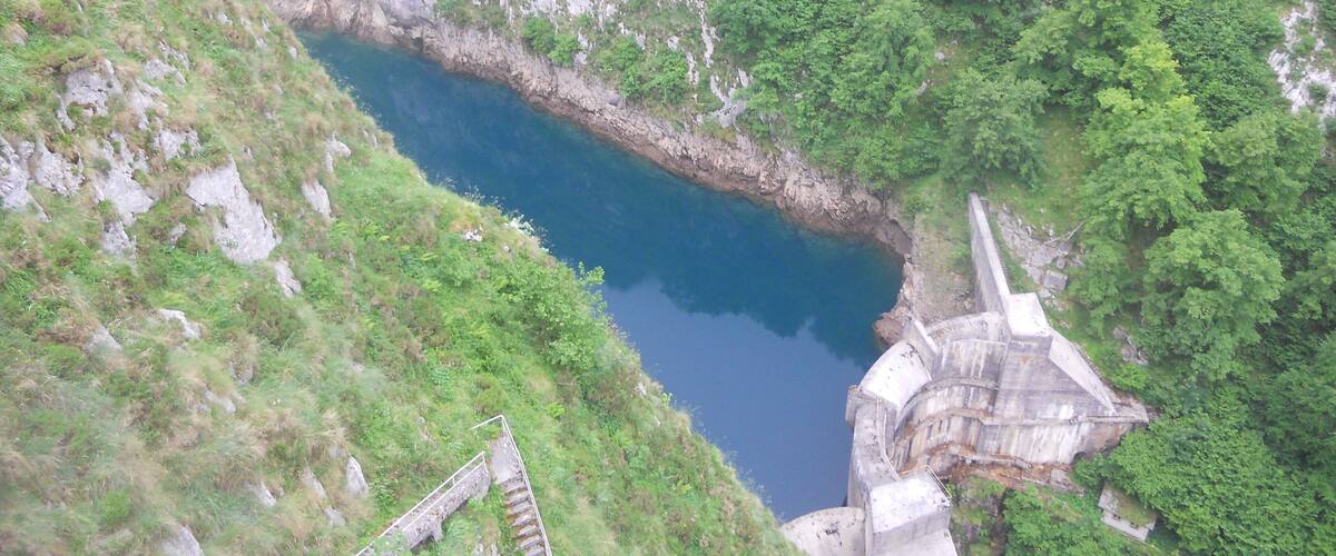 A deep blue lake surrounded by steep, rocky cliffs and lush greenery.