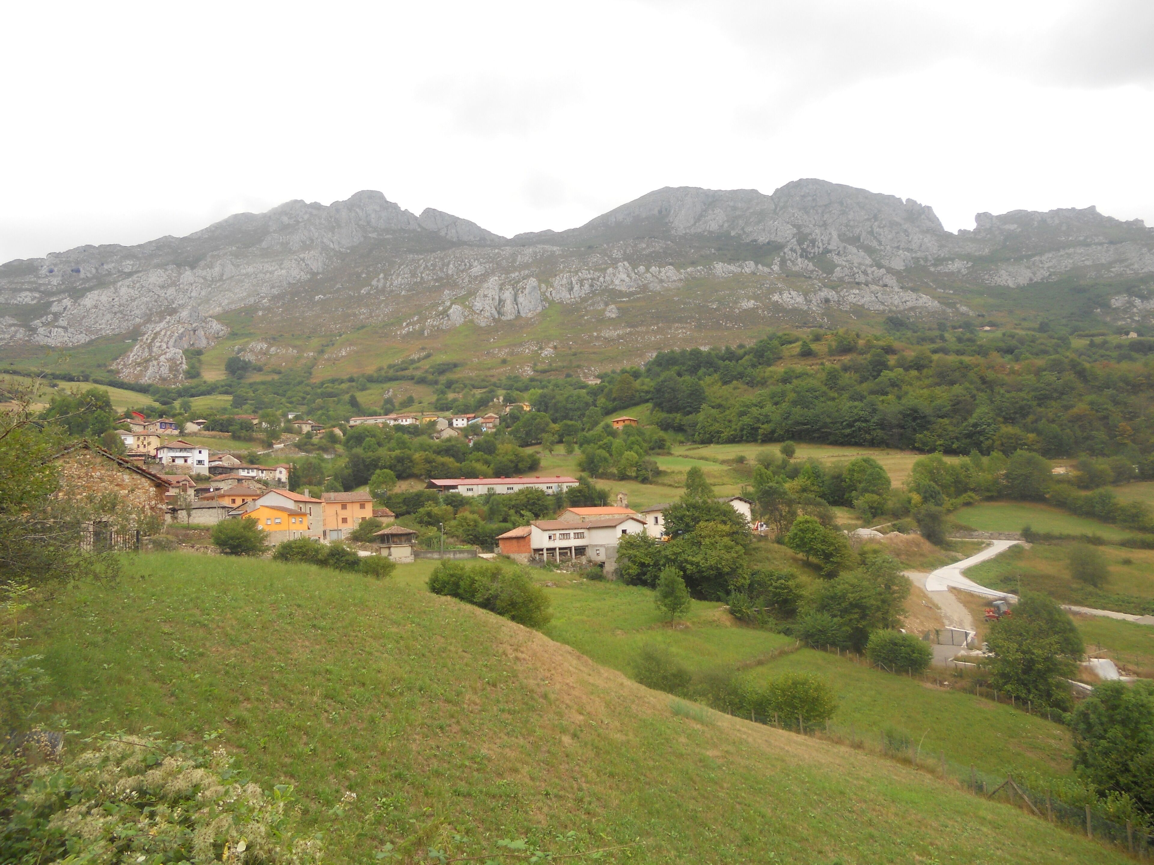 A village nestled in a valley with mountains in the background.