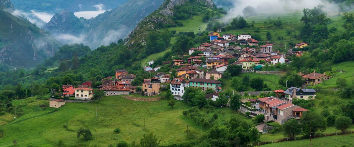 Un pueblo enclavado en un valle rodeado de montañas, con un lago al fondo.