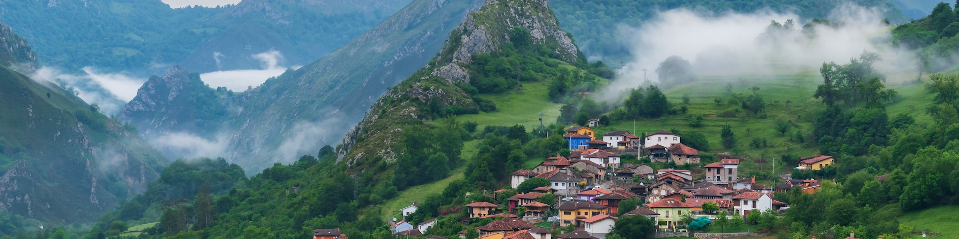 A village nestled in a valley surrounded by mountains, with a lake in the background.