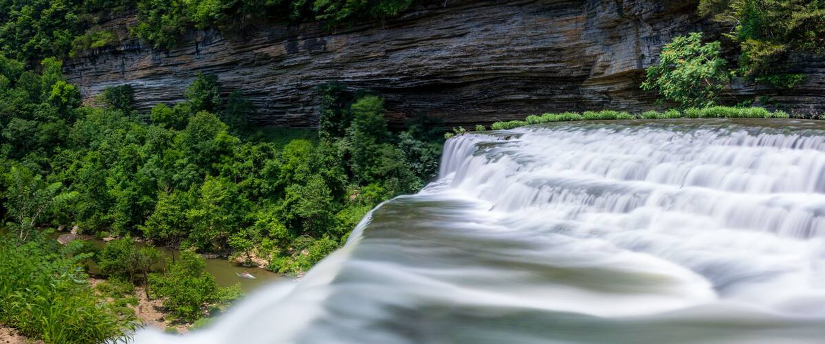 A waterfall cascading over a rocky cliff surrounded by lush greenery.