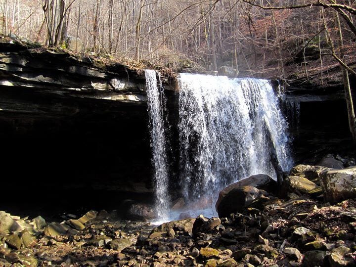 A waterfall cascading over a rocky ledge surrounded by trees.