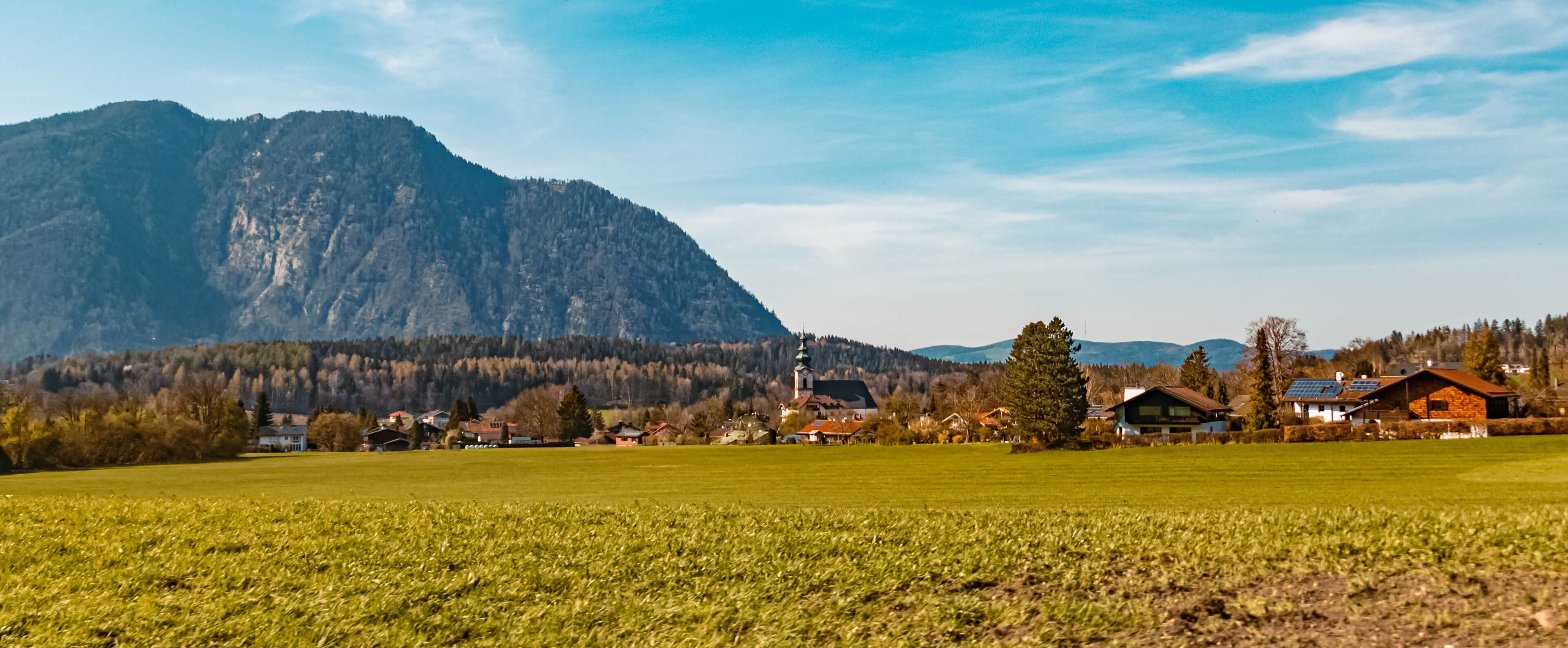 A rural landscape with a mountain, a church, and houses.