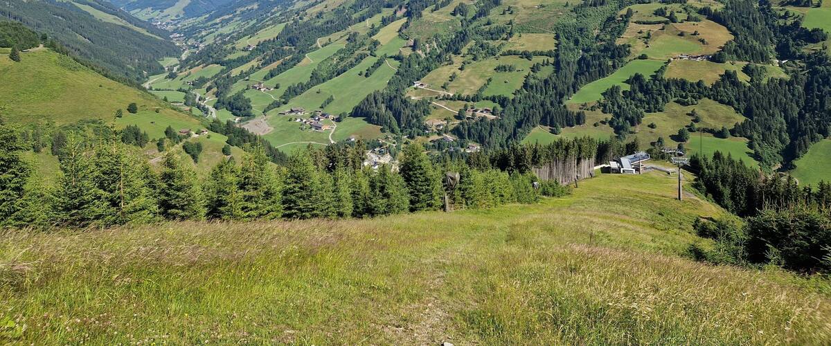 A mountainous landscape with green valleys, scattered houses, and dense forests.