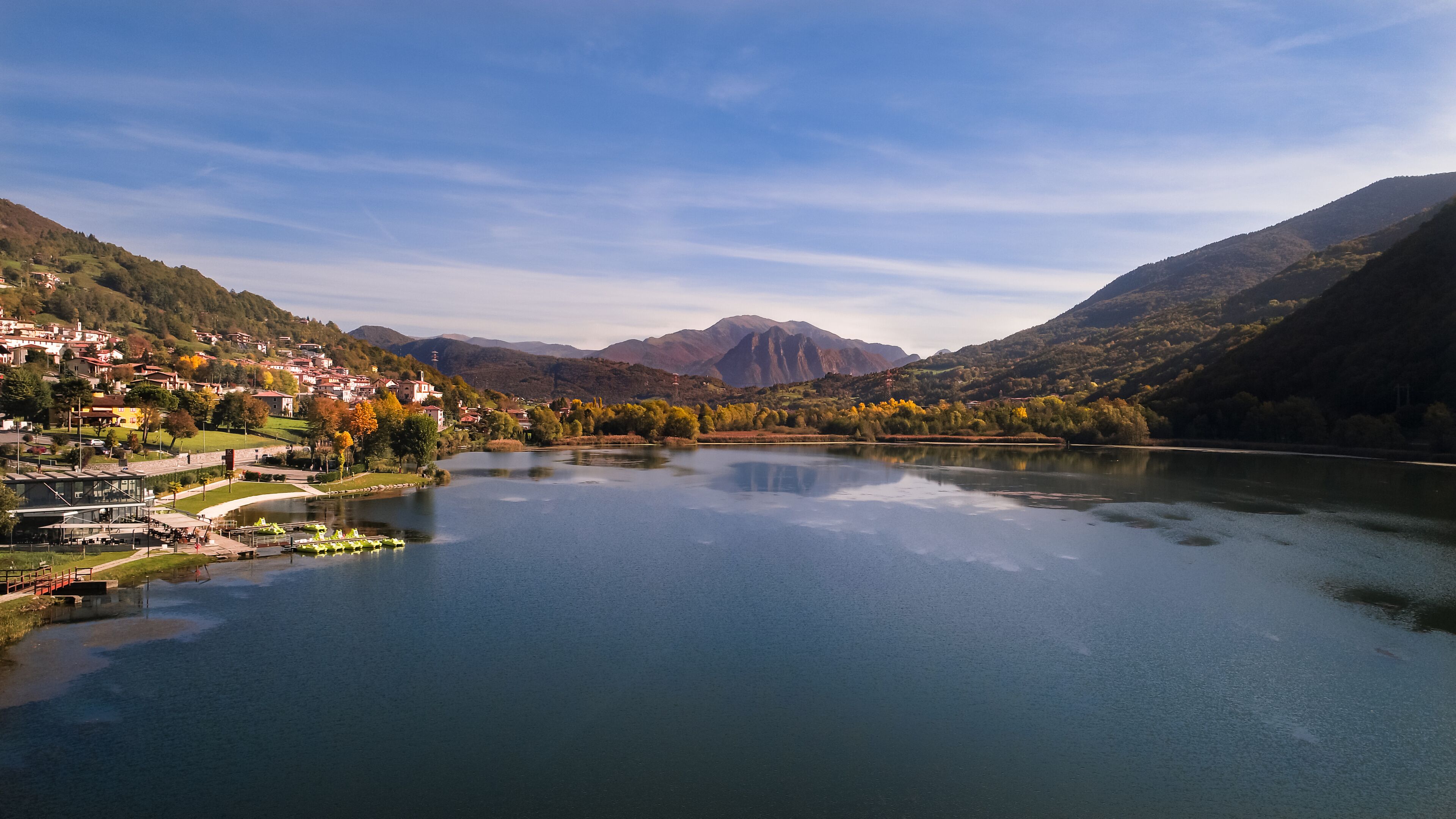 A calm river with a town on the left and mountains in the background.